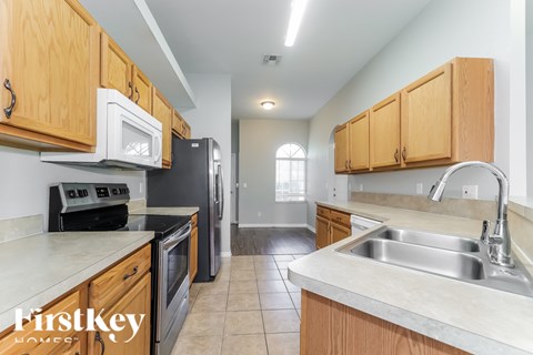 A kitchen with wooden cabinets and a white microwave above the stove.