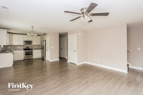 A spacious kitchen and living room with a ceiling fan and light fixture.