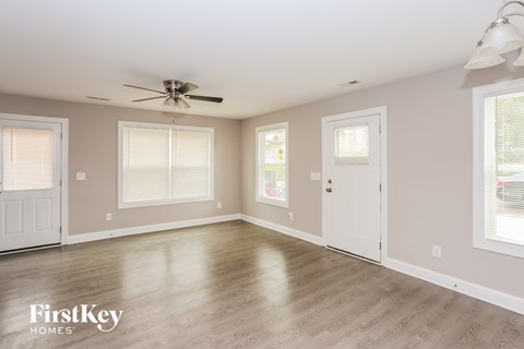 A spacious room with a fan on the ceiling and a door on the right side.
