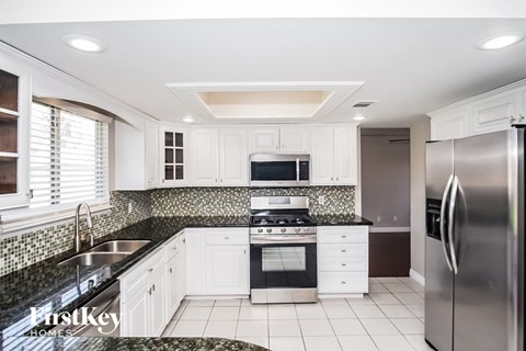 A modern kitchen with white cabinets and a black countertop.