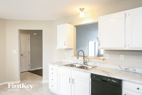 A kitchen with white cabinets and a marble countertop.