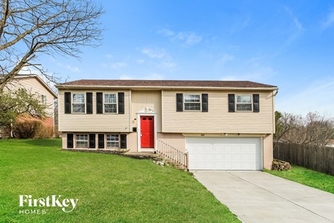 a beige house with a red door and a white garage door