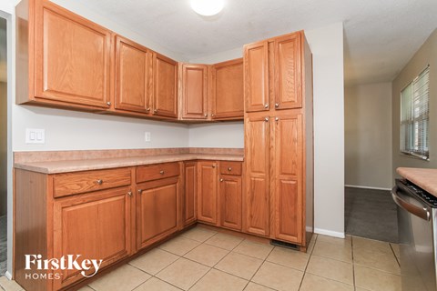 a kitchen with wooden cabinets and tiled floors and a sink