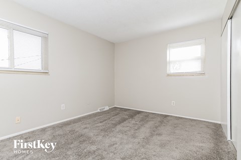 a bedroom with carpet and two windows