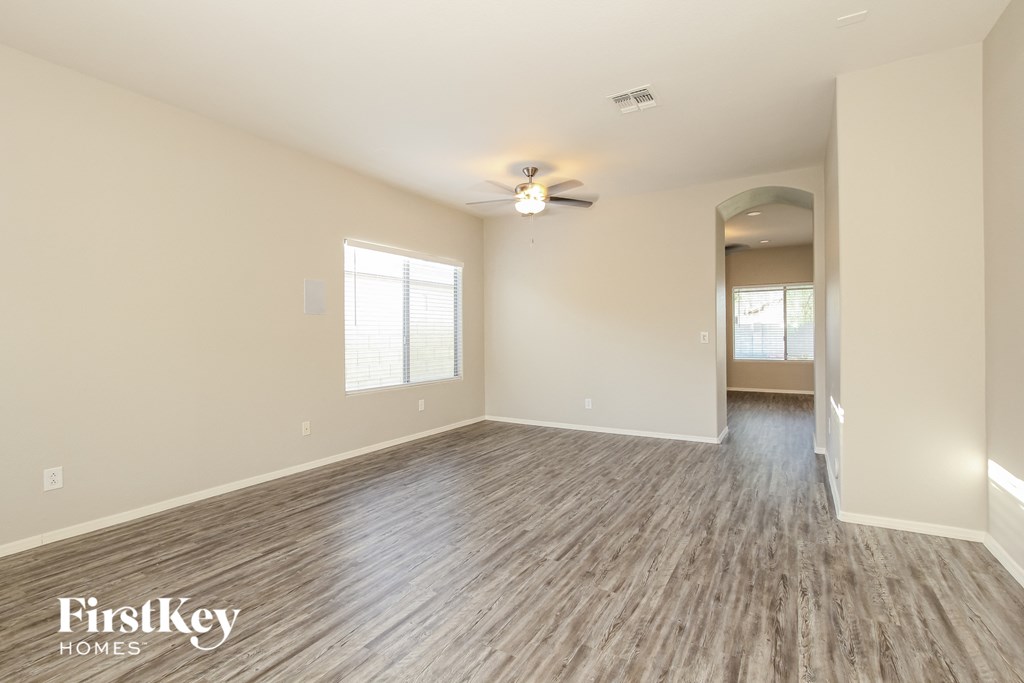 the living room of an empty house with wood flooring and a ceiling fan