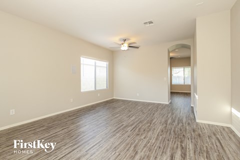 the living room of an empty house with wood flooring and a ceiling fan