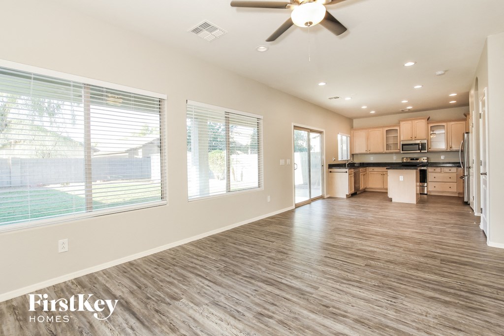 the living room and kitchen of an empty house with a ceiling fan