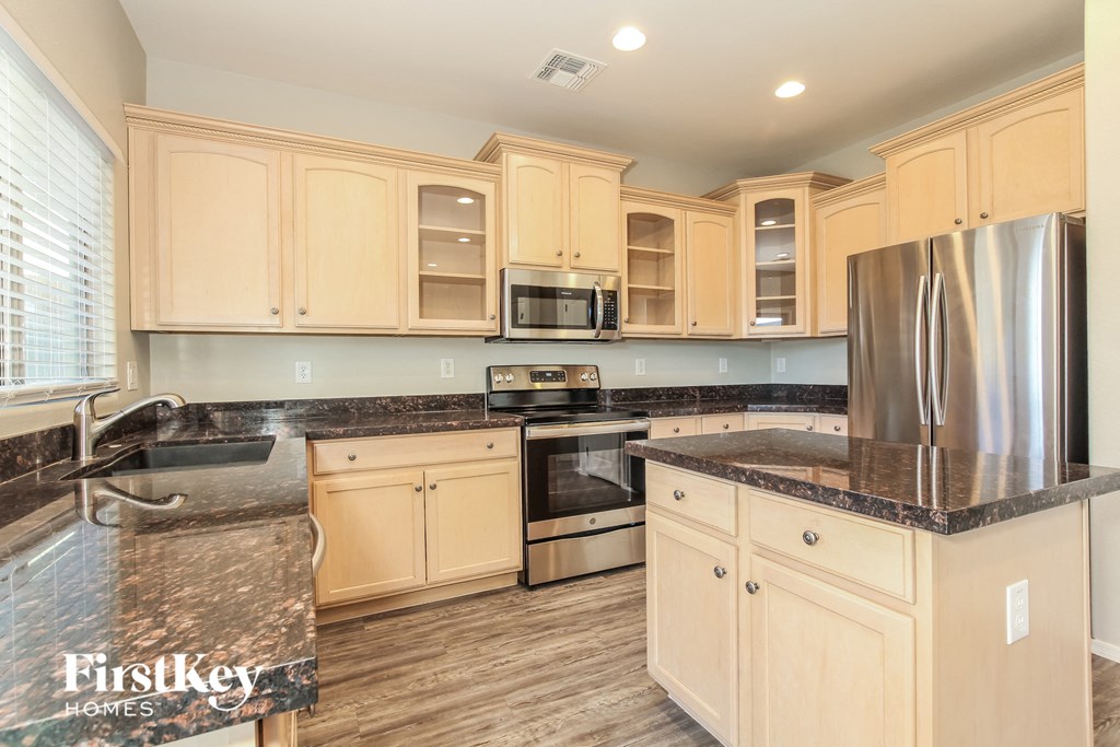 a kitchen with white cabinets and granite counter tops and stainless steel appliances
