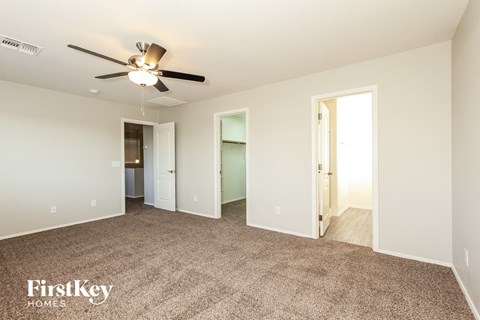 a spacious living room with carpet and a ceiling fan