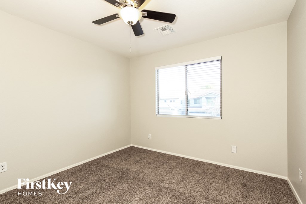 a bedroom with carpet and a ceiling fan and a window