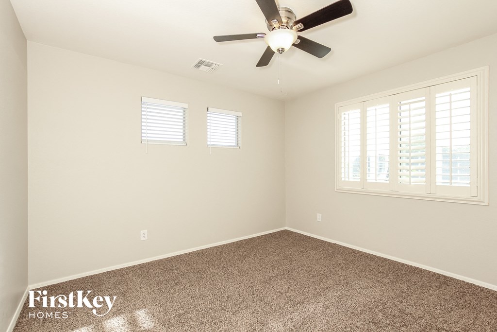 an empty room with a ceiling fan and window