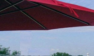 a swimming pool with chairs and a red umbrella
