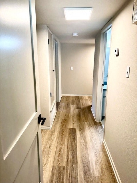 A long hallway with wood floors and white walls.