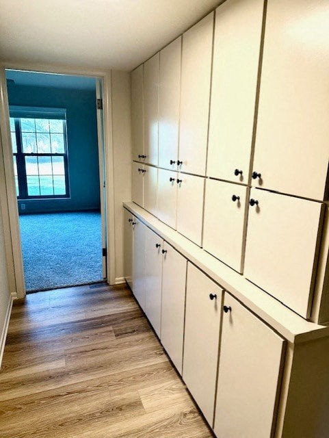 A hallway with white cupboards and a doorway leading to a balcony.