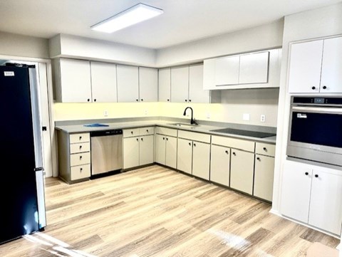 A kitchen with white cabinets and a black refrigerator.