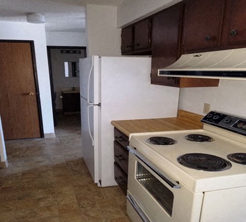 A kitchen with a white stove and refrigerator.