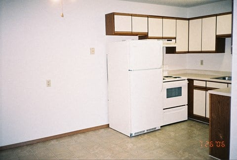 an empty kitchen with a white refrigerator and white cabinets