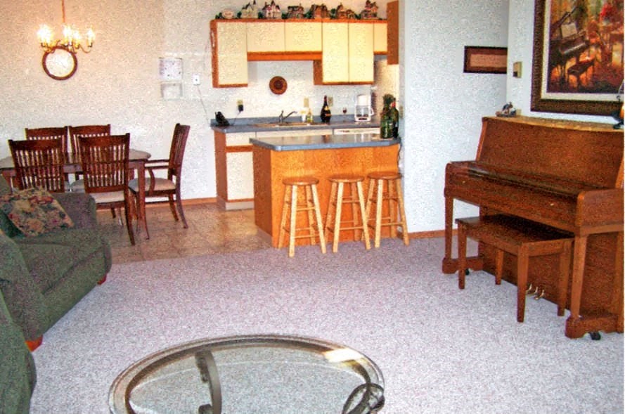 a living room with a kitchen and a piano