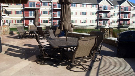 a patio with chairs and tables and an umbrella