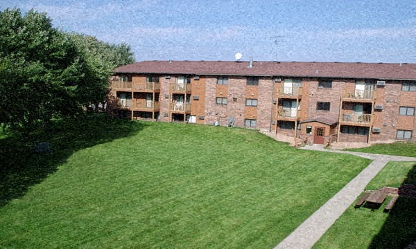 an aerial view of a large brick apartment building with a lawn