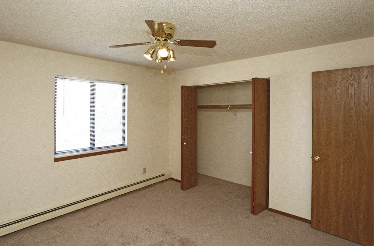 a bedroom with a ceiling fan and a door to a closet