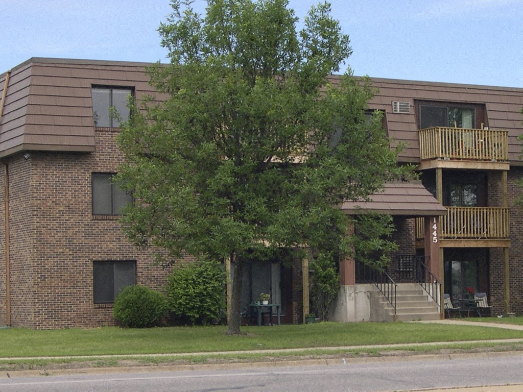 a brick apartment building with a tree in front of it