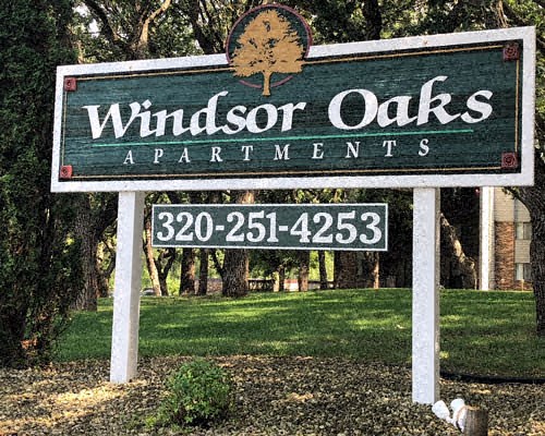 a sign for windsor oaks apartments in front of a lawn