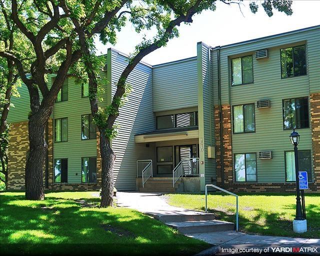 a green apartment building with trees in front of it