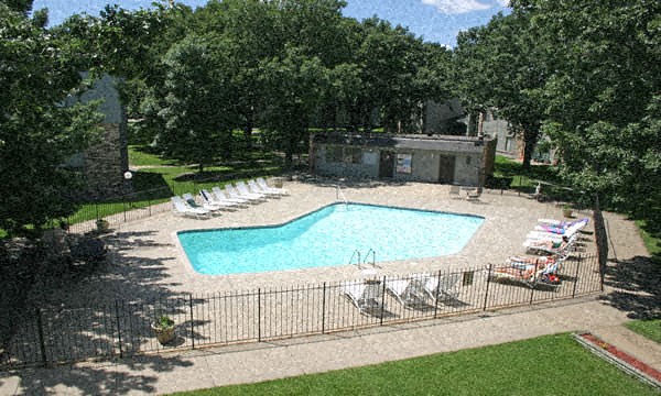 an aerial view of a pool with chairs and a fence