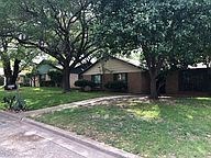 A house with a driveway and trees in front of it.