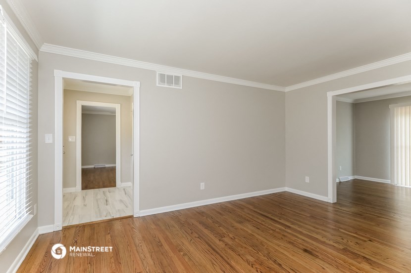 the living room of a house with wooden floors and white walls