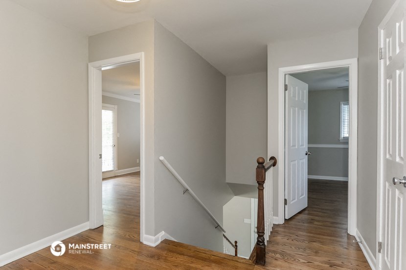 a bedroom with a staircase and a hallway with a door to a room and a