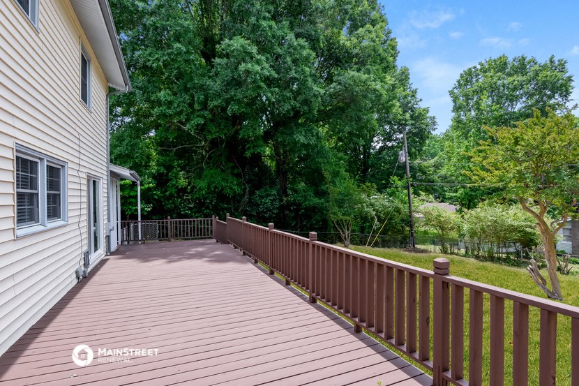 a long wooden deck with a house and trees