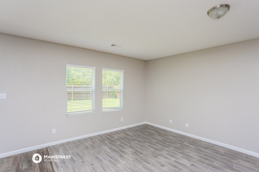 the spacious living room with vinyl flooring and two windows