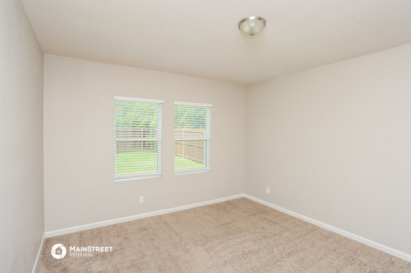 the spacious living room with carpet and two windows