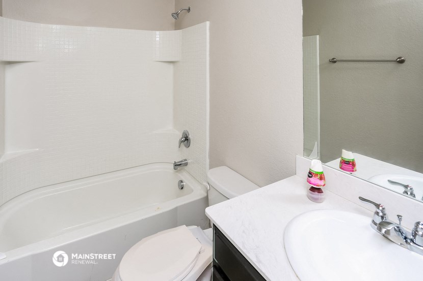 a bathroom with a tub sink and toilet and a mirror