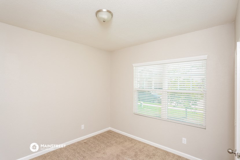 a bedroom with a large window and a carpeted floor