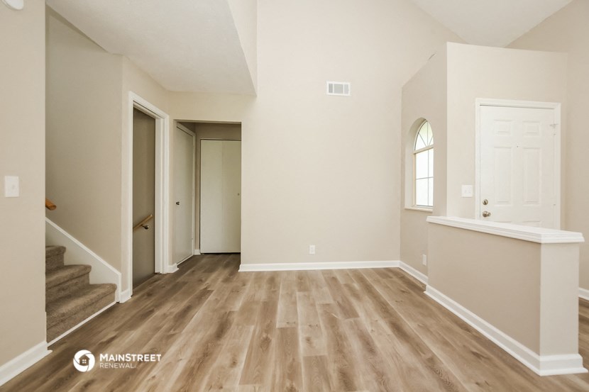 the spacious living room with hardwood flooring and white walls