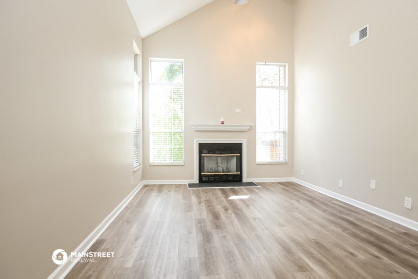 an empty living room with a fireplace and wooden floors