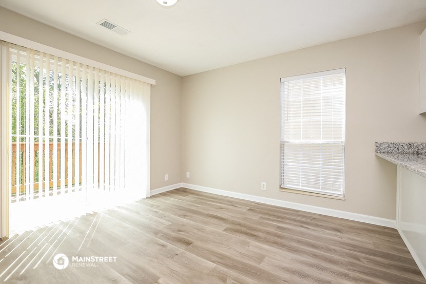 an empty living room with wood flooring and a window
