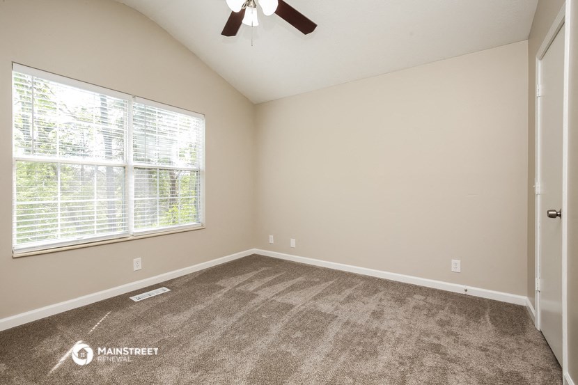 the spacious living room has carpeted floors and a large window