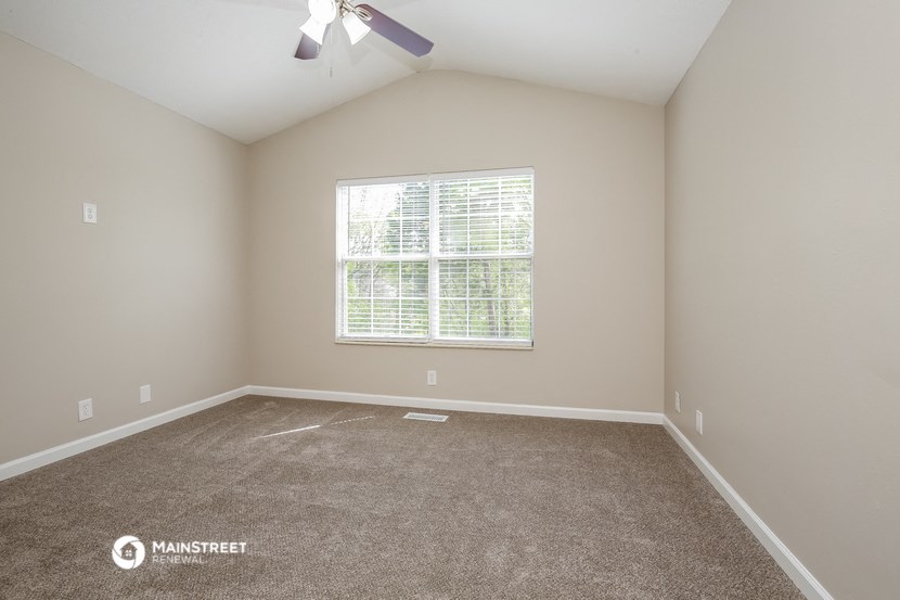the spacious living room with carpeting and a window