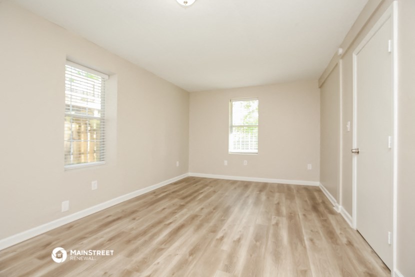 the spacious living room with hardwood flooring and two windows