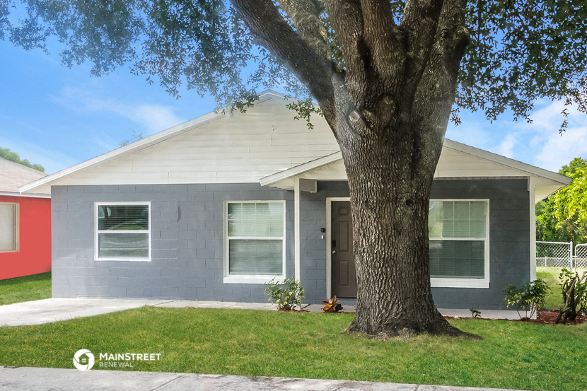 a gray house with a large tree in front of it
