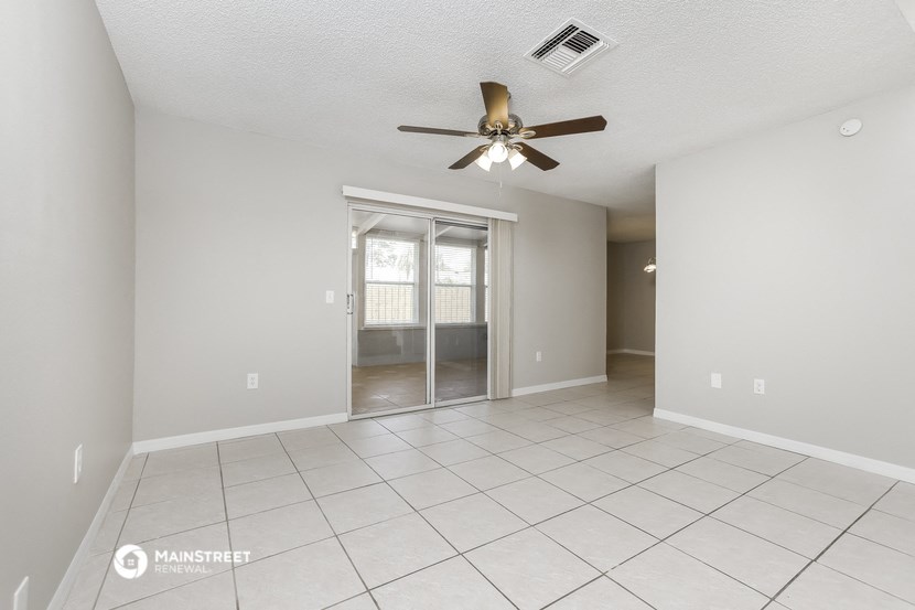 the spacious living room with ceiling fan and tiled floor