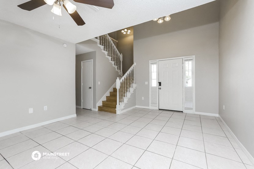 an empty living room with a staircase and a ceiling fan