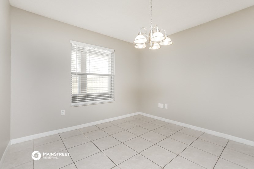 the spacious living room with a chandelier and tiled floor