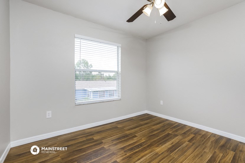 the living room of an apartment with wood flooring and a ceiling fan