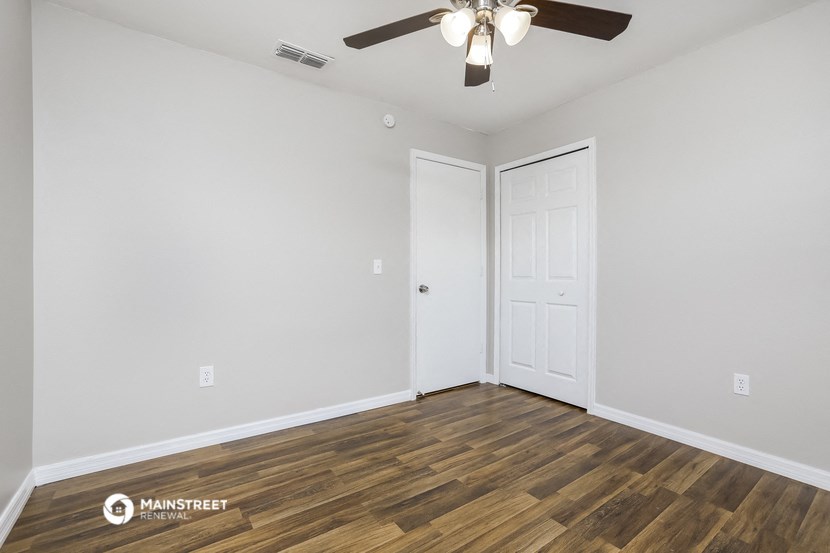 the living room of an apartment with wood flooring and a ceiling fan