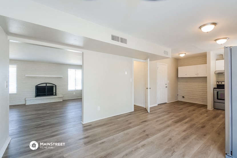the living room and dining room of an apartment with wood flooring and a fireplace